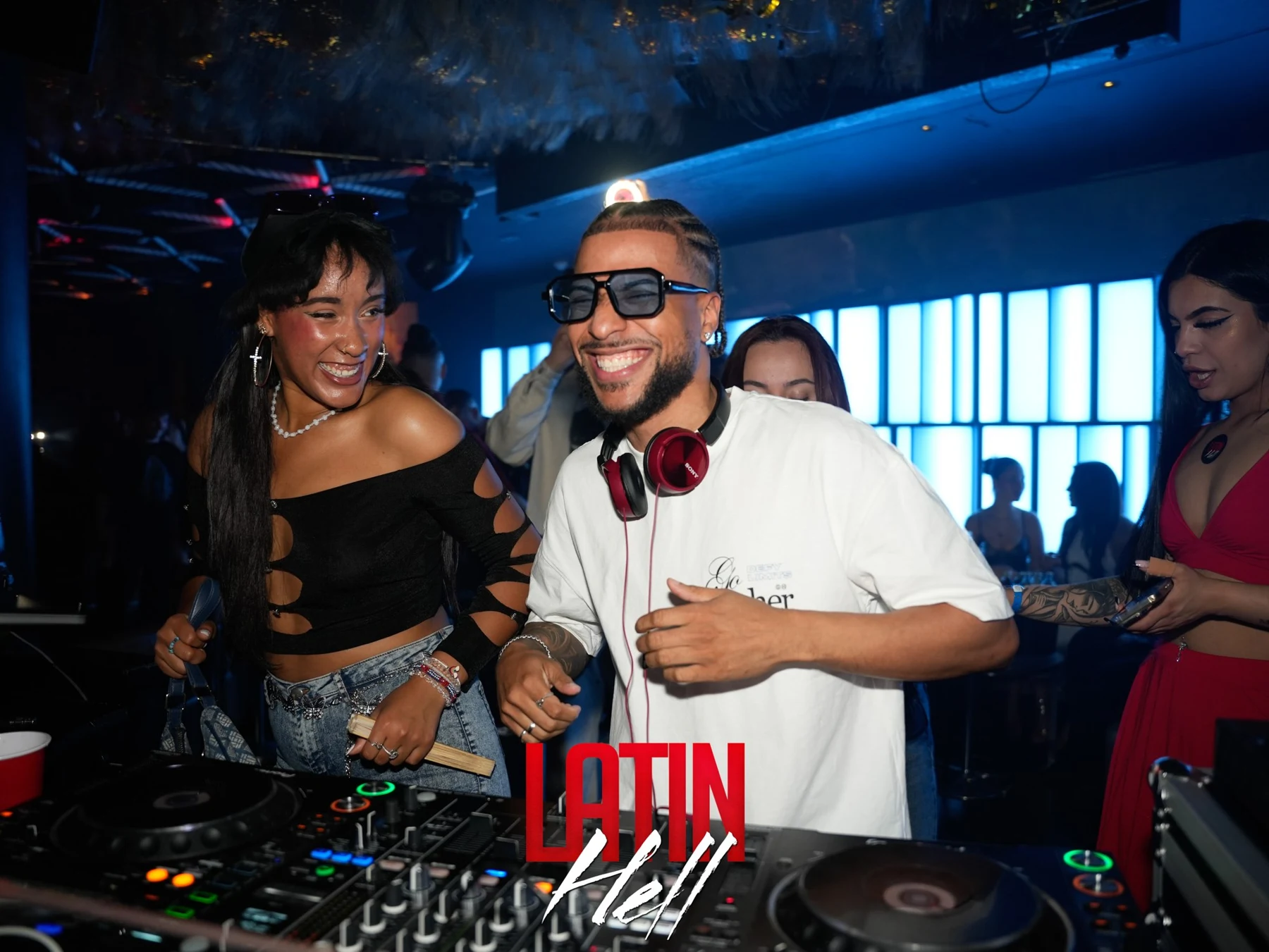 Lächelnder DJ und Gäste am Mischpult bei Latin Hell